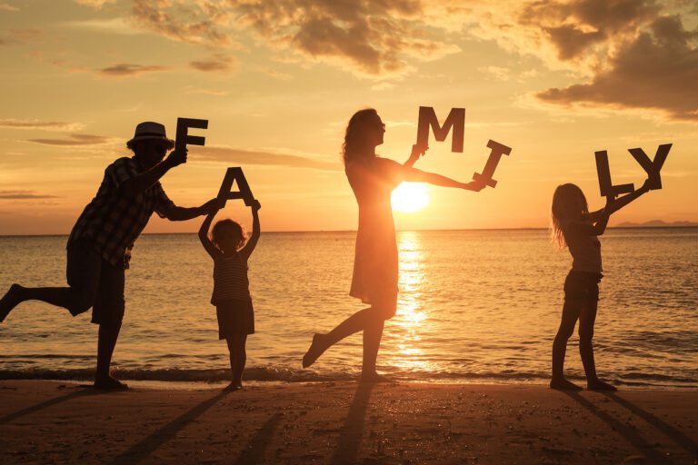 Happy,Family,Standing,On,The,Beach,At,The,Sunset,Time.