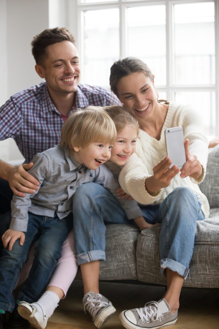 Happy,Mother,Taking,Family,Selfie,With,Husband,And,Kids,Looking